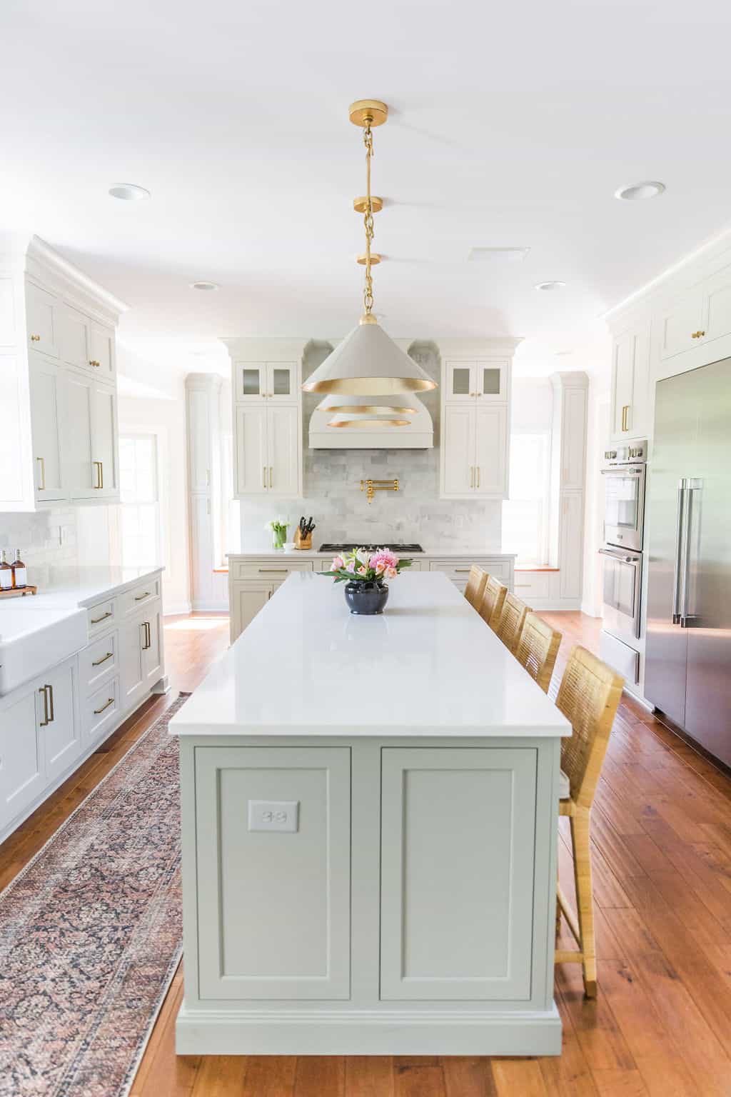 Nicholas Design Build | A remodeled white kitchen with a large island and chairs.
