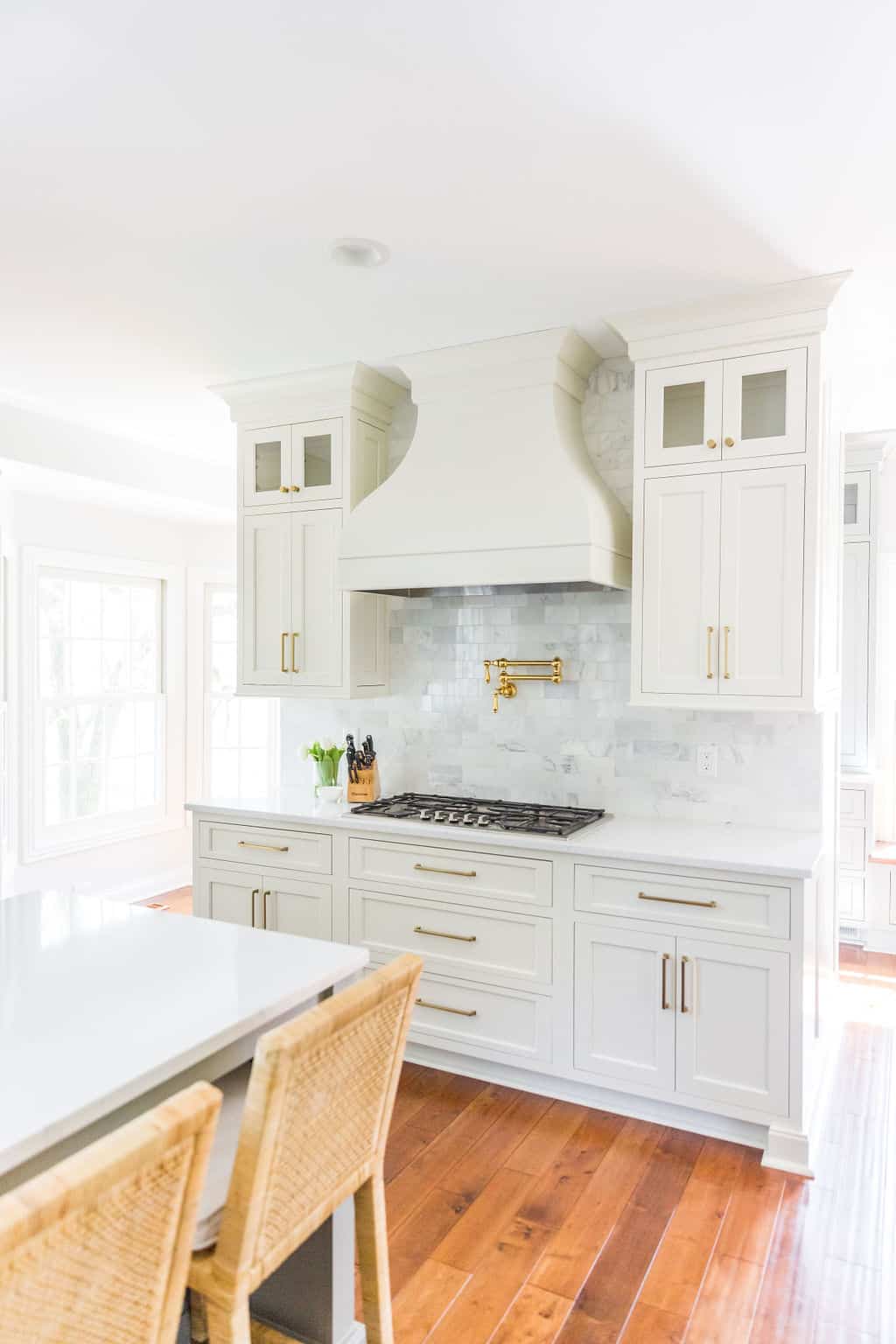 Nicholas Design Build | Remodel a white kitchen with wood floors and wicker chairs.