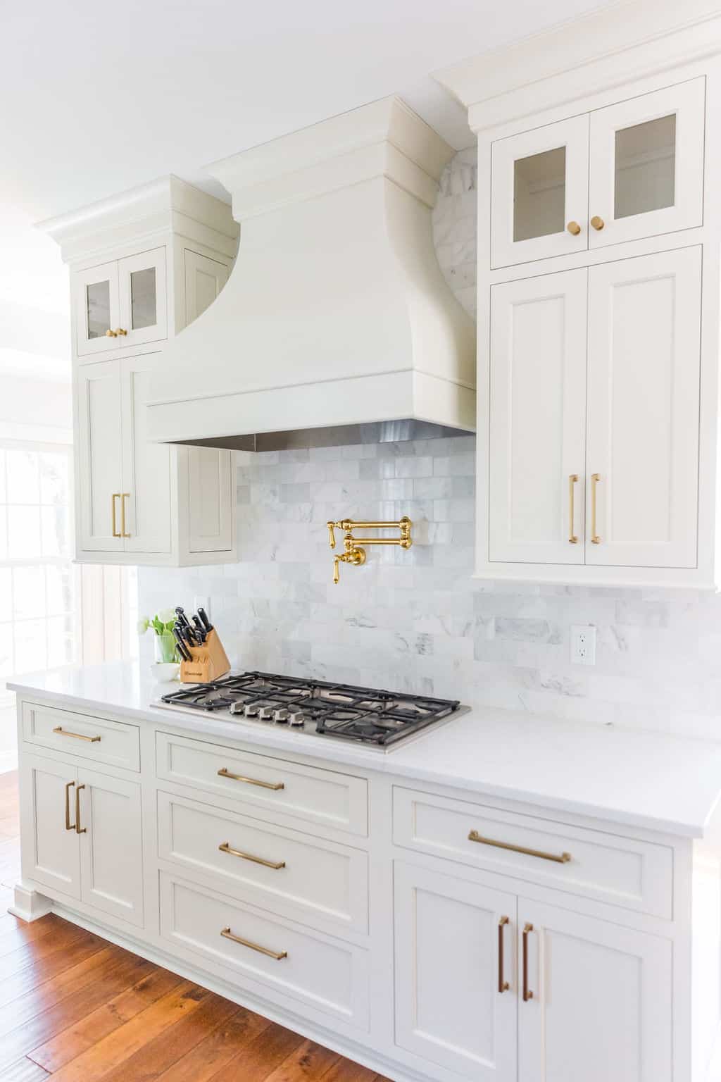 Nicholas Design Build | Remodel of a kitchen with white cabinets and a gold hood.