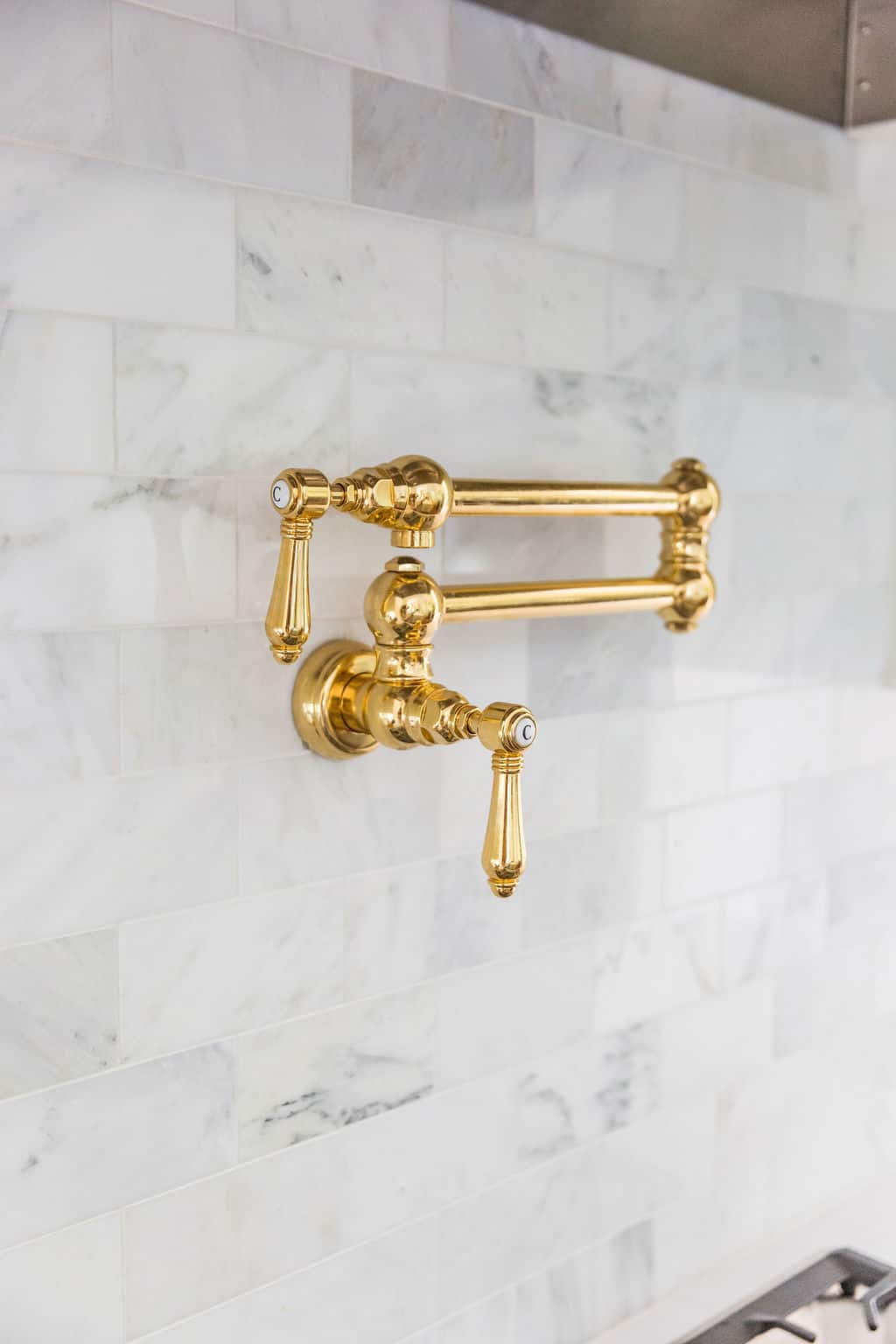 Nicholas Design Build | A remodeled kitchen with a gold faucet on the wall.