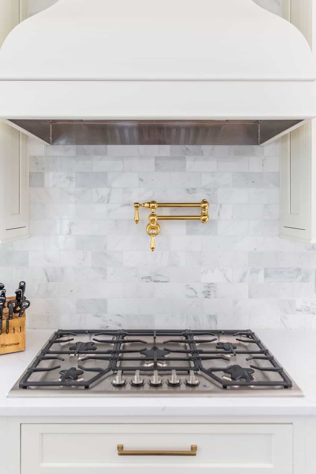 Nicholas Design Build | A white kitchen with a gold hood over the stove, undergoing a remodel.