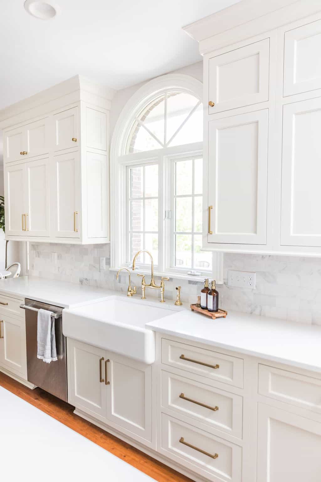 Nicholas Design Build | A remodelled kitchen with white cabinets and a gold sink.