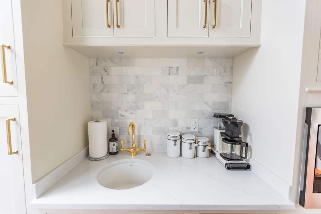 Nicholas Design Build | Remodel: A white kitchen with marble counter tops and gold hardware, newly renovated to perfection.