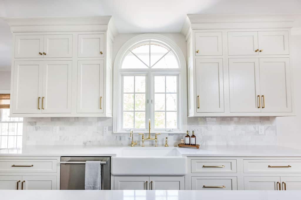 Nicholas Design Build | A remodel of a kitchen with white cabinets and a gold sink.
