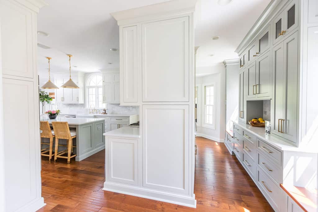 Nicholas Design Build | A kitchen with white cabinets and hardwood floors undergoing a remodel.