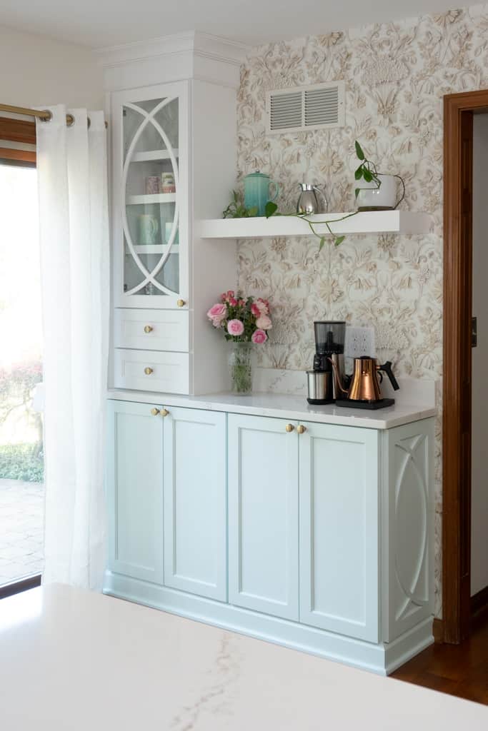 Nicholas Design Build | A remodeled kitchen with blue cabinets and flowers on the counter.