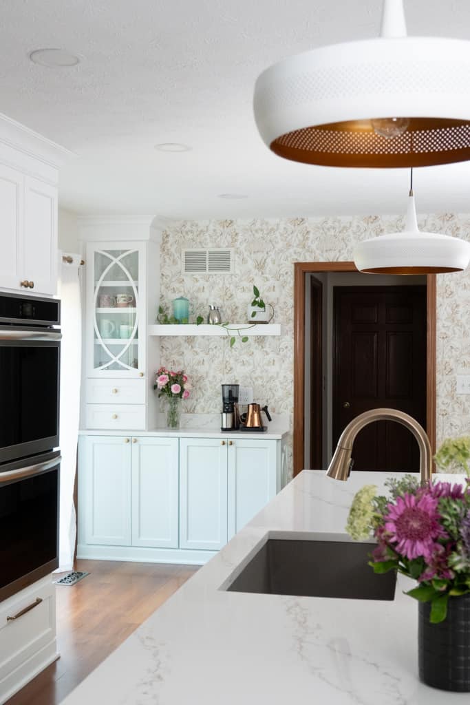Nicholas Design Build | A remodeled kitchen with marble counter tops and a white pendant light.