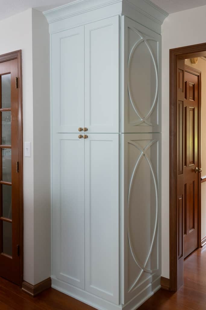 Nicholas Design Build | A white cabinet in a remodeled room with hardwood floors.