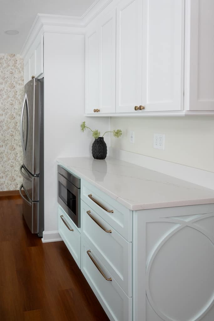 Nicholas Design Build | A remodeled kitchen with white cabinets and a microwave.