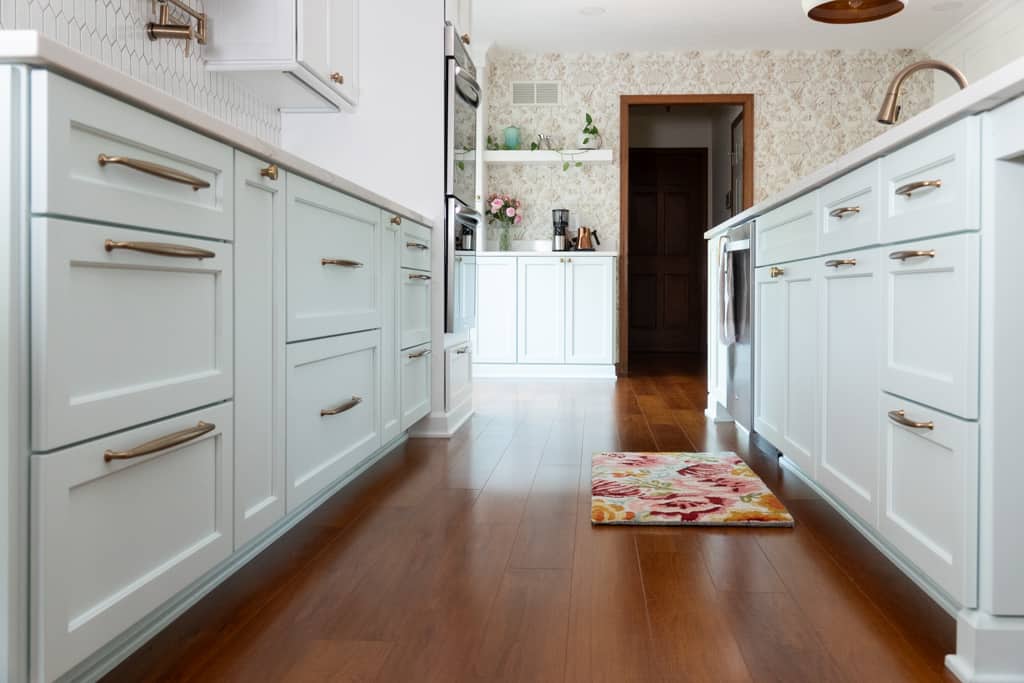Nicholas Design Build | A kitchen remodel with white cabinets and a wooden floor.