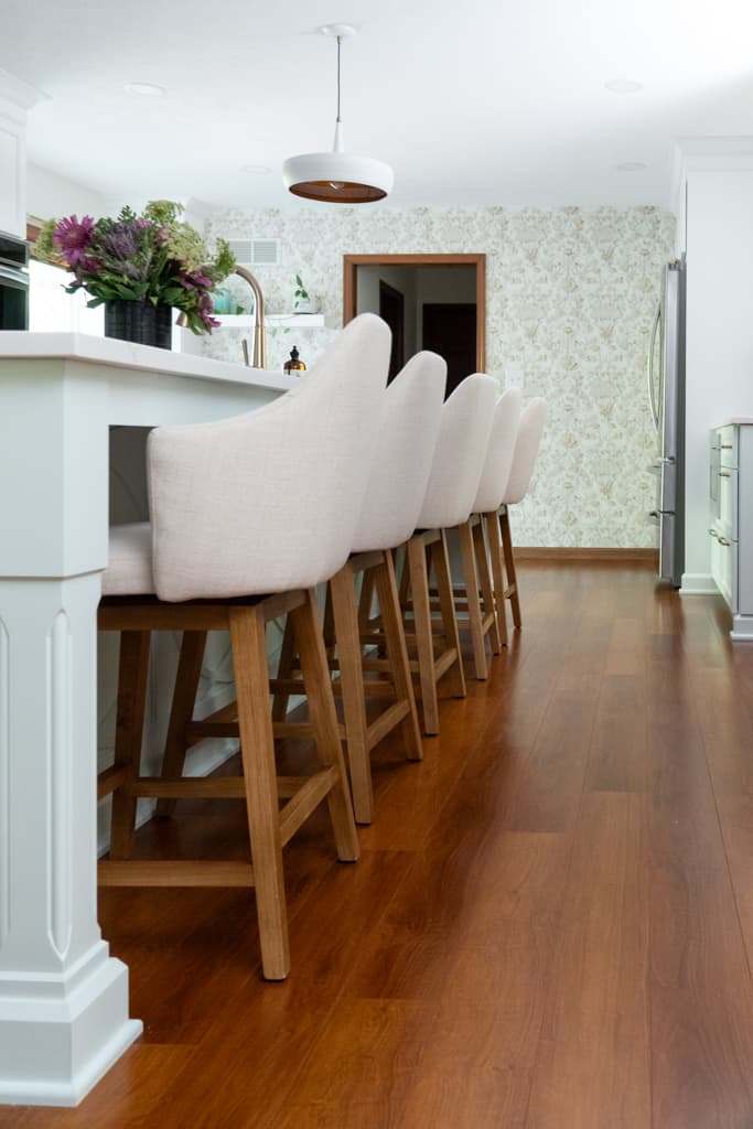 Nicholas Design Build | A white kitchen with wood floors and white stools undergoes a stunning remodel.