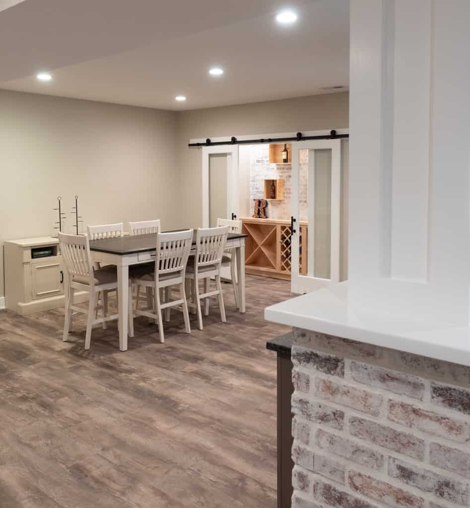 Nicholas Design Build | A dining room with wood floors and a brick wall undergoing a remodel.
