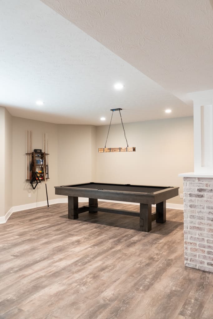 Nicholas Design Build | Remodeling a basement to create a cozy entertainment space featuring a pool table and fireplace.
