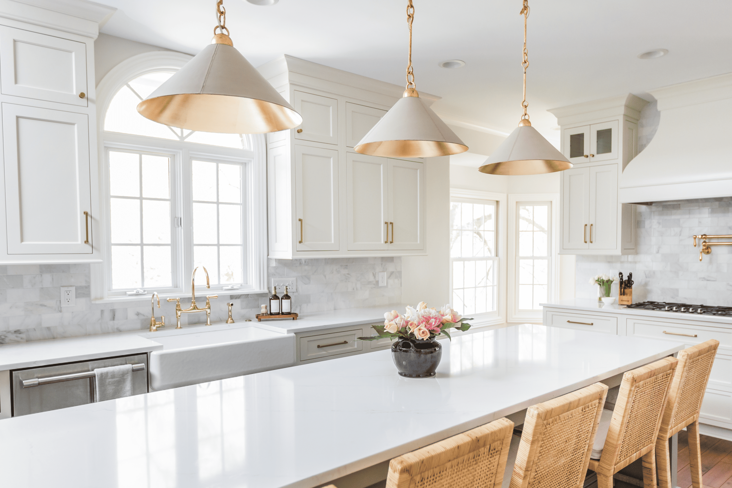 Nicholas Design Build | A kitchen with remodelled white cabinets and gold pendant lights.