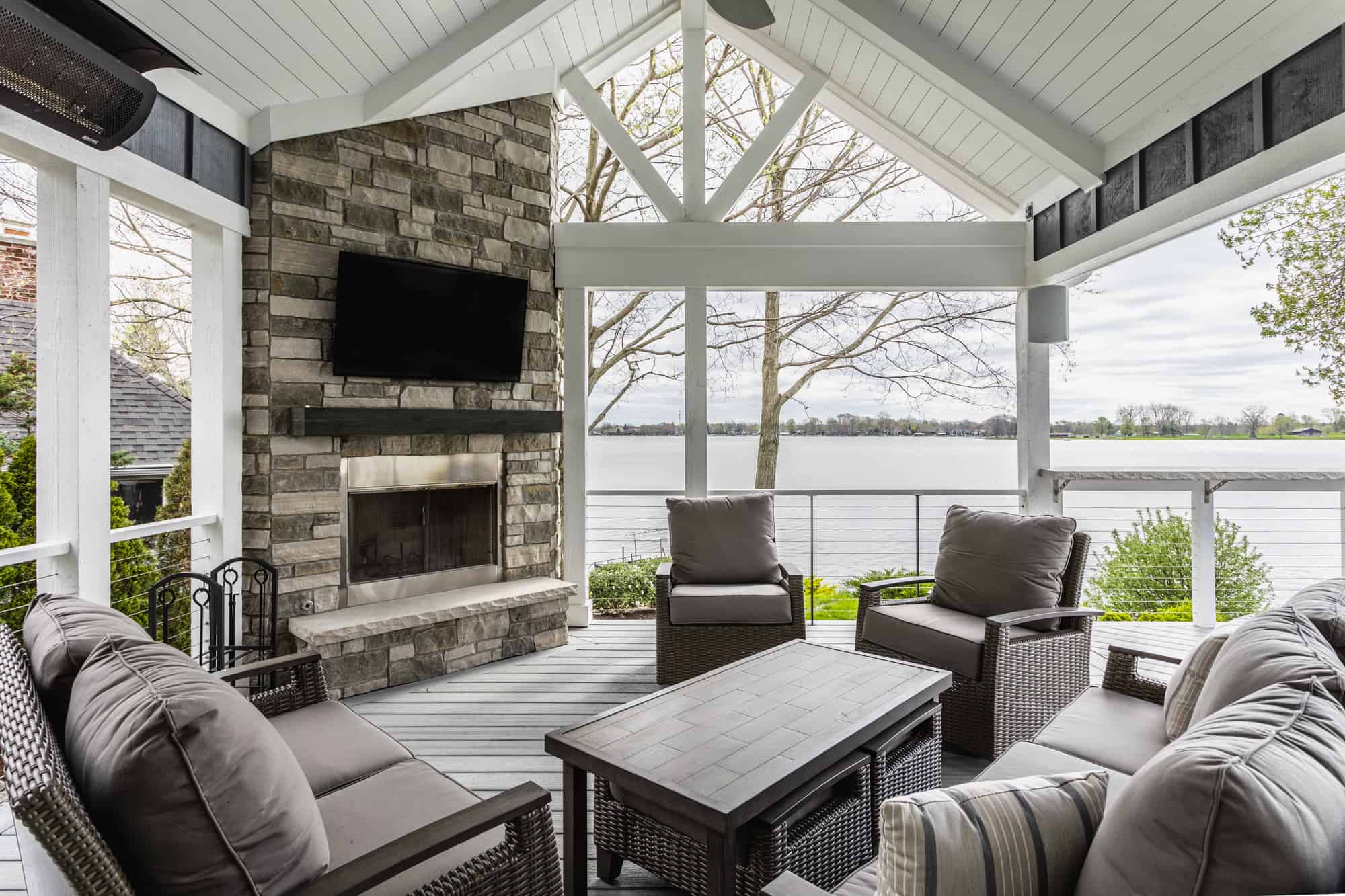 Nicholas Design Build | A remodelled screened-in porch with furniture and a fireplace.