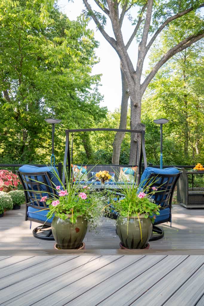 Nicholas Design Build | A wooden deck with blue chairs and potted plants.