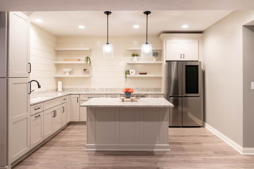 Nicholas Design Build Carmel Basement | A basement kitchen with white cabinets and stainless steel appliances.