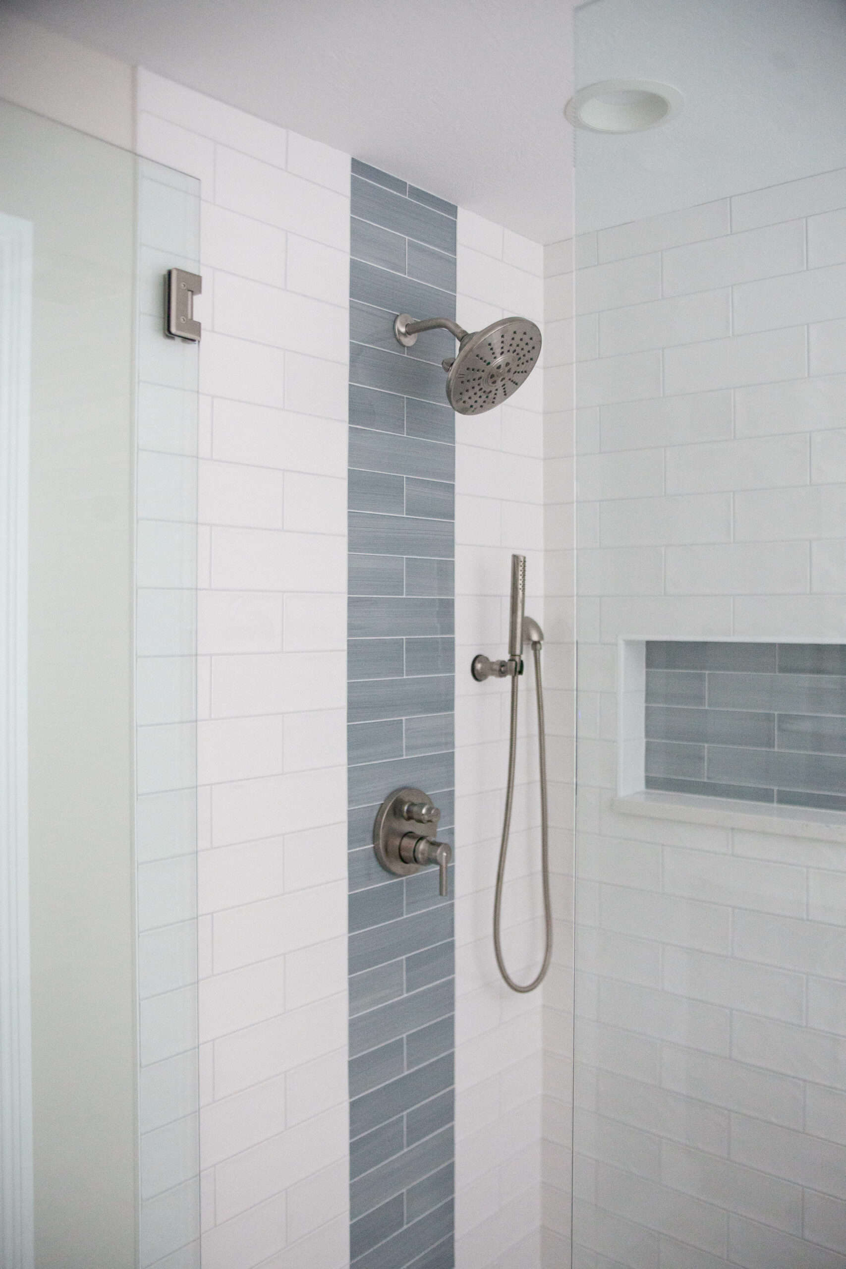 Nicholas Design Build | A blue and white tiled shower with a glass shower head.