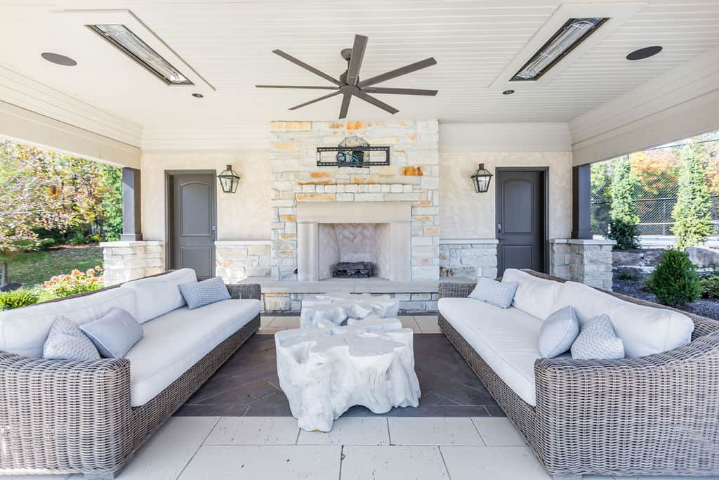 Nicholas Design Build | An outdoor living room with wicker furniture and a fireplace.