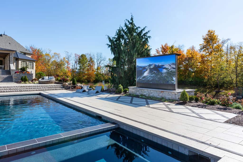Nicholas Design Build | A large screen on a stone wall next to a swimming pool.