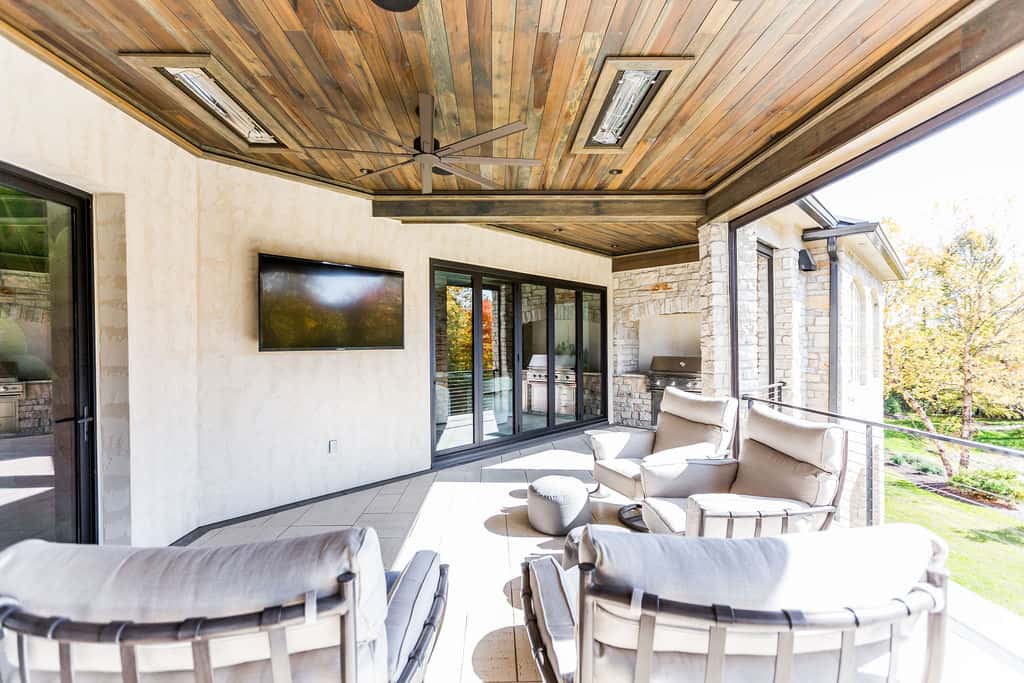 Nicholas Design Build | A covered patio with a tv and chairs.