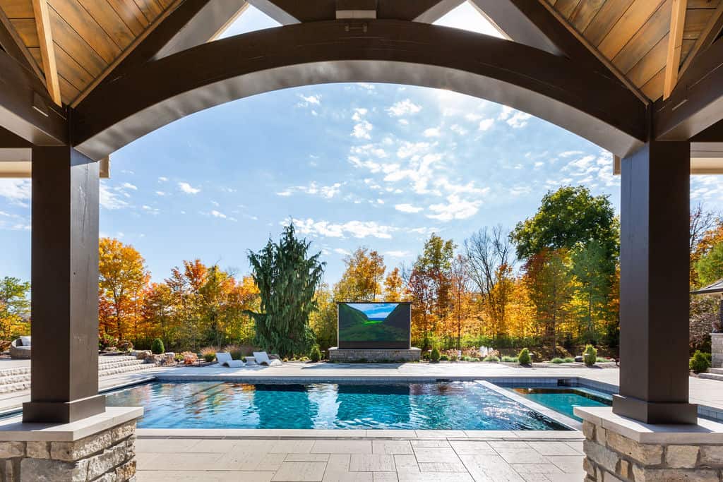 Nicholas Design Build | A pool with a large screen and a fireplace.