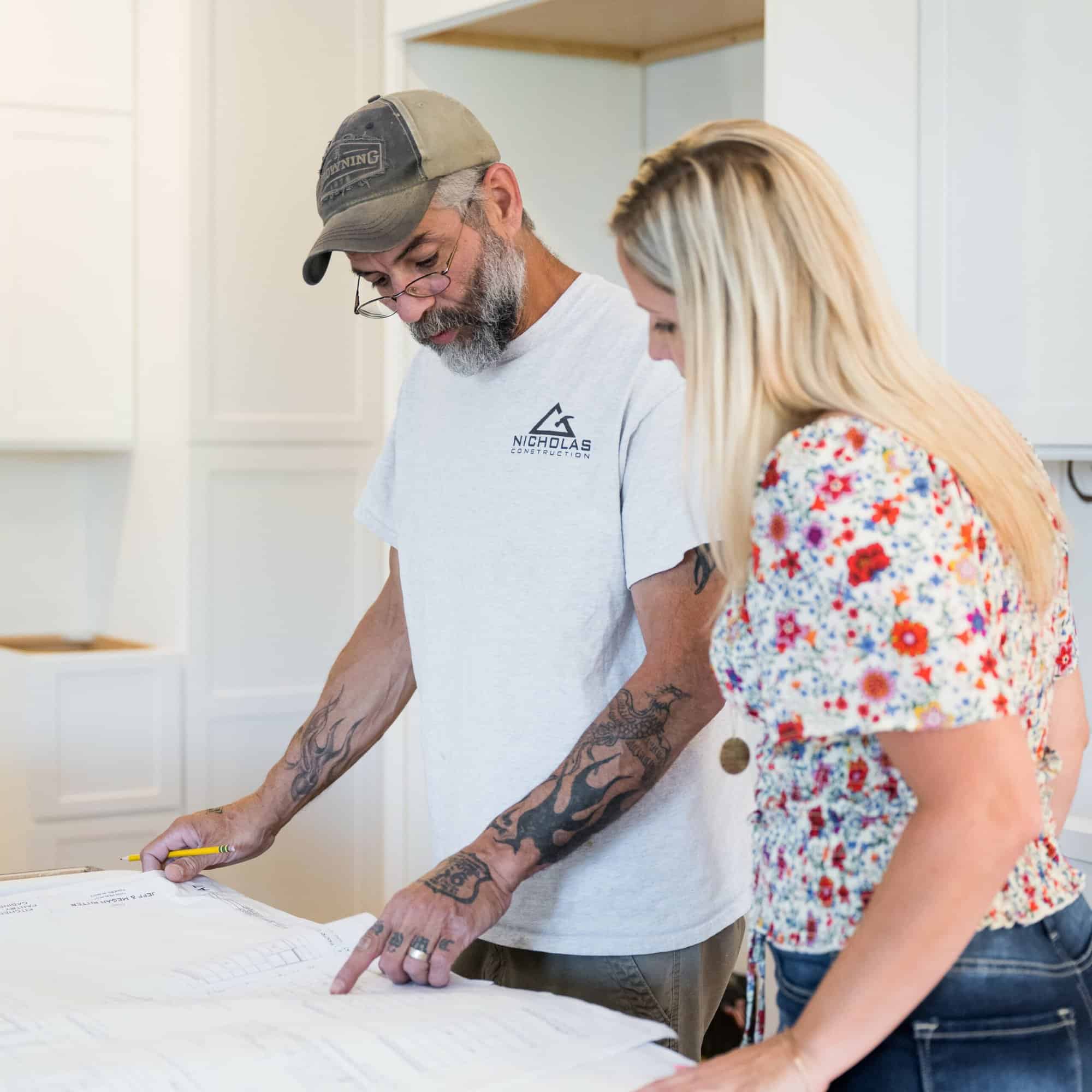 Nicholas Design Build | A man and woman looking at blueprints in a kitchen.