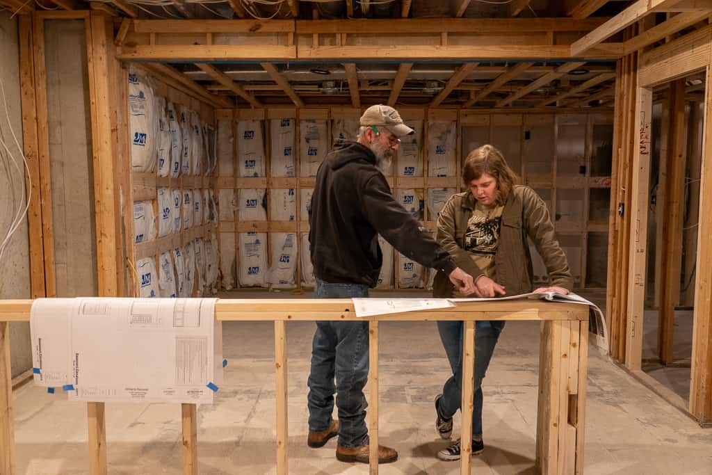 Nicholas Design Build | Two people standing in a room with wood framing.
