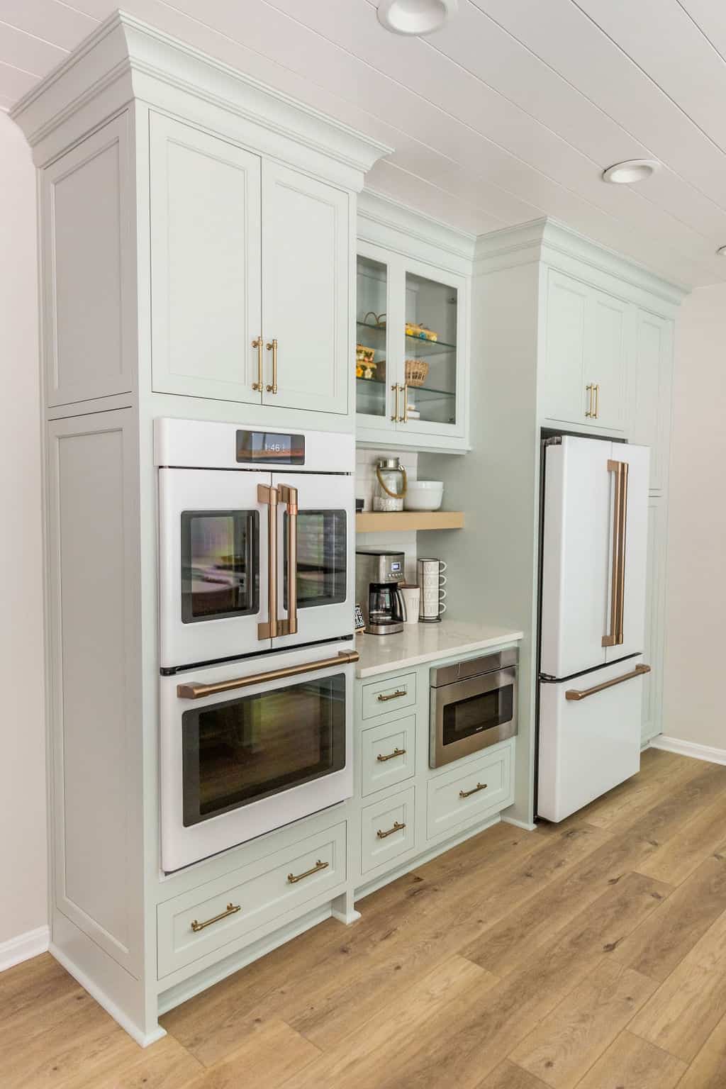 Nicholas Design Build | A modern kitchen with white cabinets, built-in appliances, and hardwood flooring.