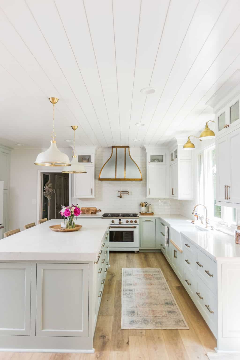 Nicholas Design Build | Bright and airy kitchen with white cabinetry, a central island, and gold pendant lighting.