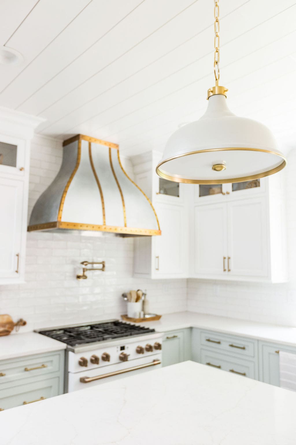 Nicholas Design Build | A stylish kitchen interior with white cabinetry, marble countertops, and a modern pendant light.