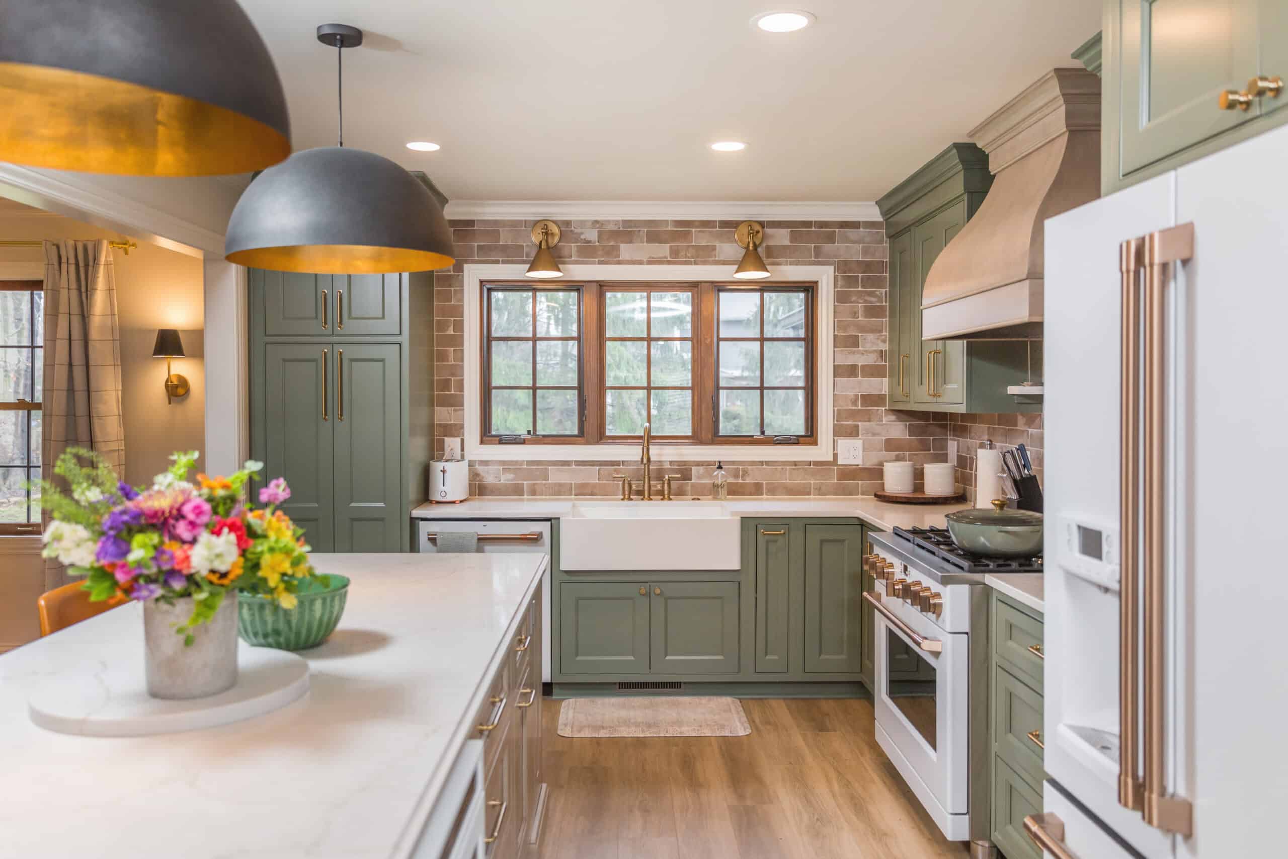 Nicholas Design Build | Modern kitchen with green cabinets, white countertops, and pendant lighting.