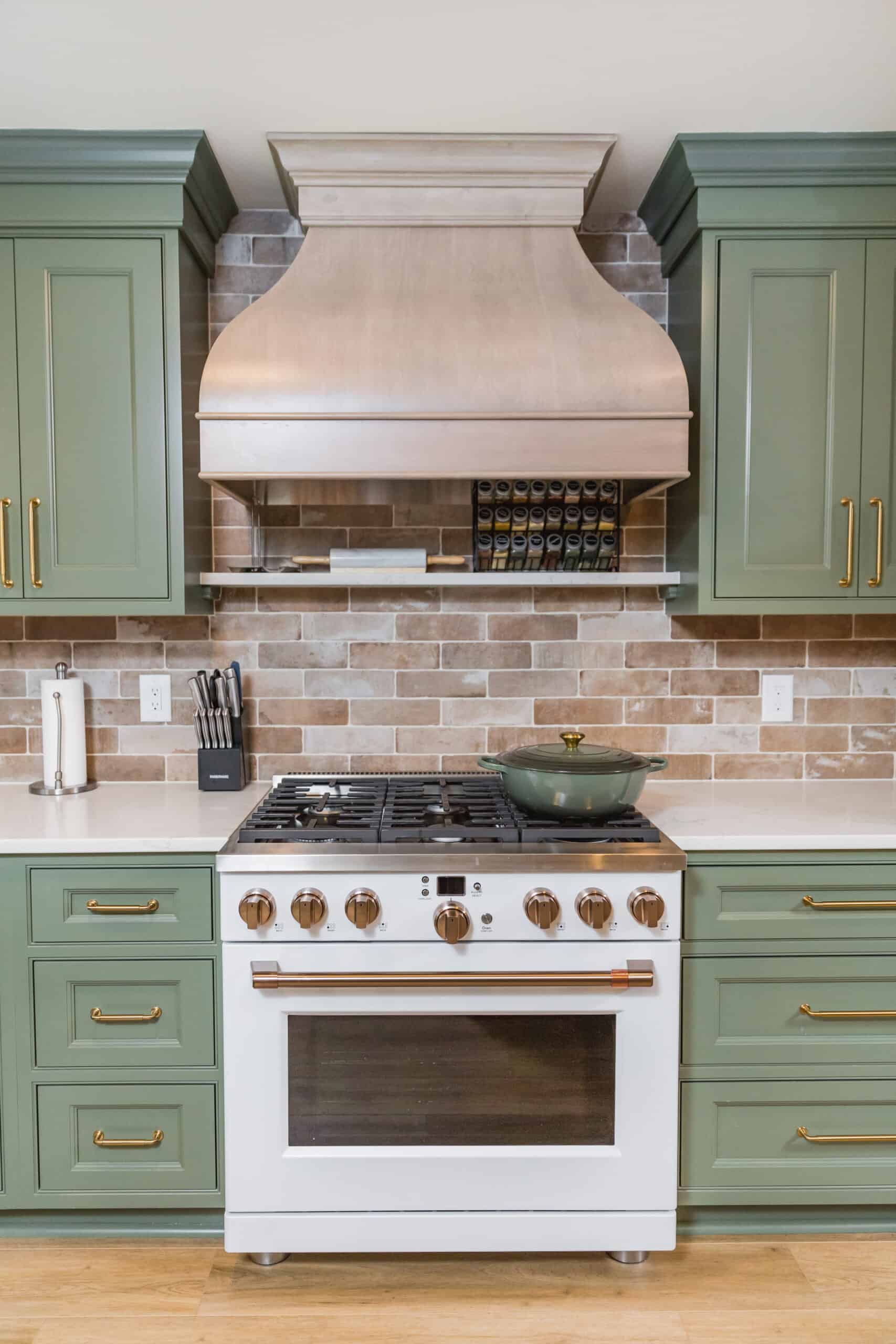 Nicholas Design Build | Modern kitchen with green cabinets, stainless steel appliances, and copper range hood.