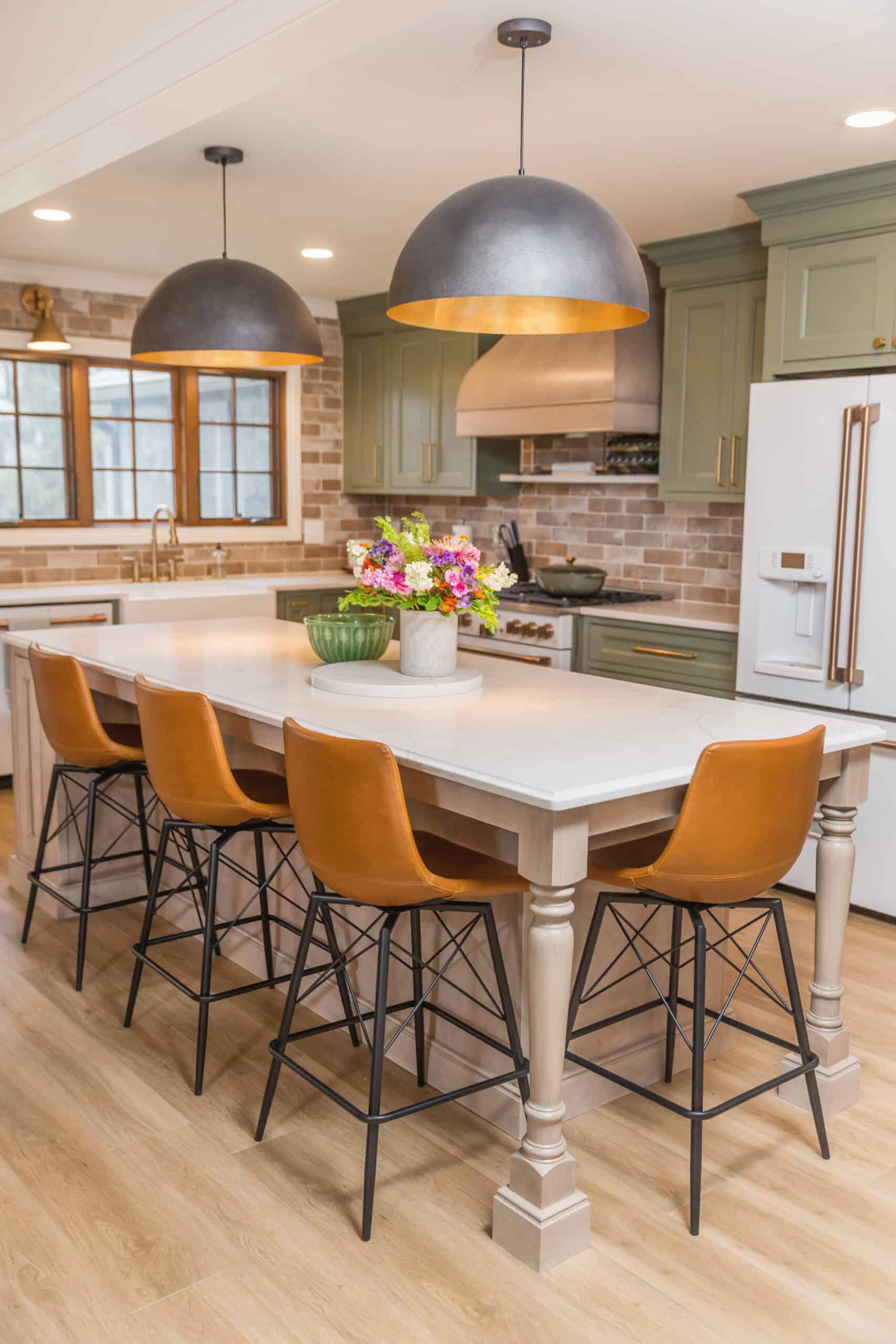 Nicholas Design Build | A modern kitchen with a central island featuring tan leather stools and pendant lights.