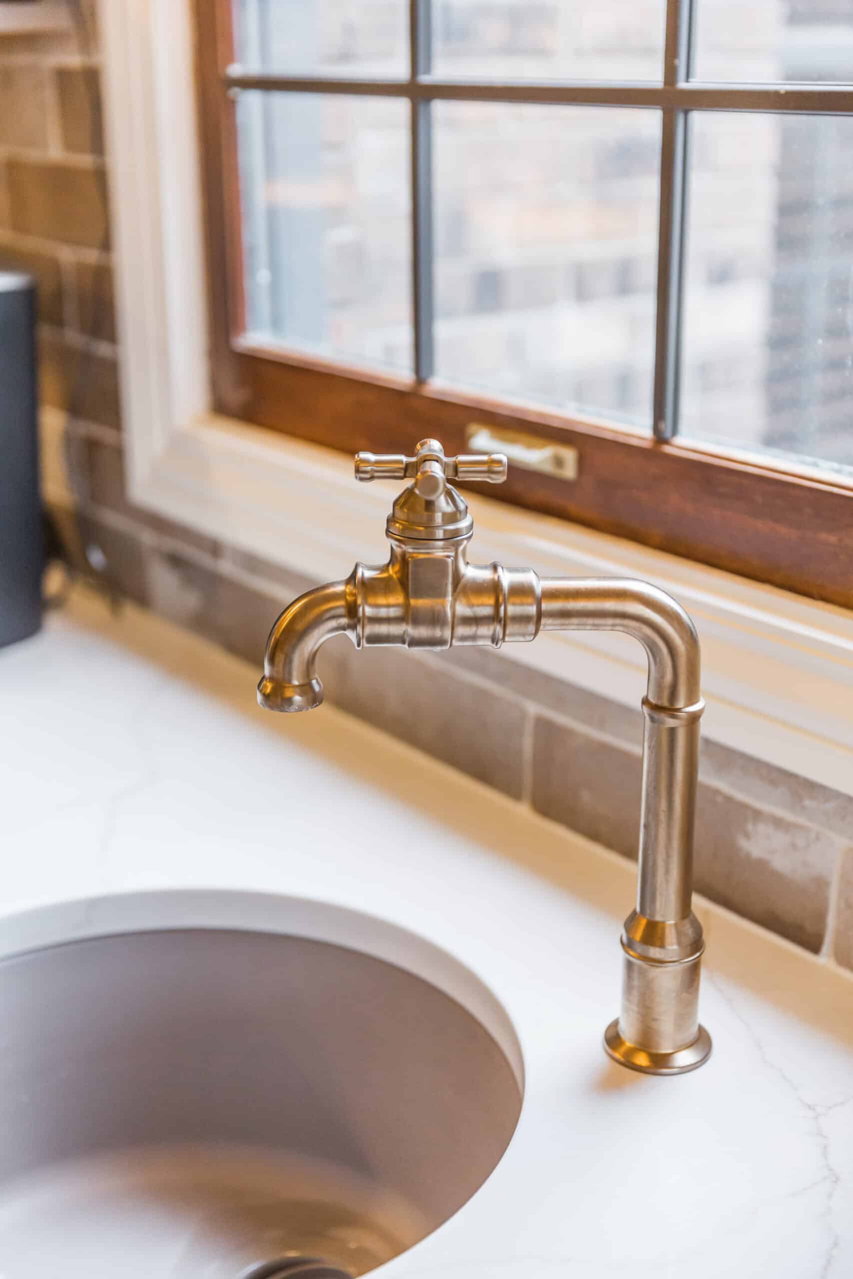 Nicholas Design Build | Vintage-style brass faucet over a sink near a window.