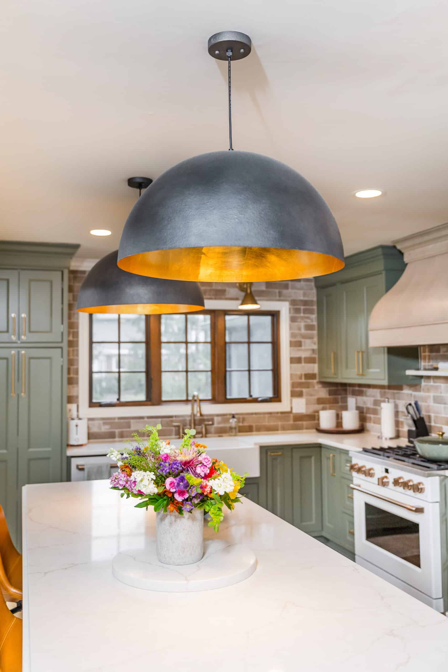 Nicholas Design Build | Modern kitchen with a large pendant light over an island with a floral centerpiece.