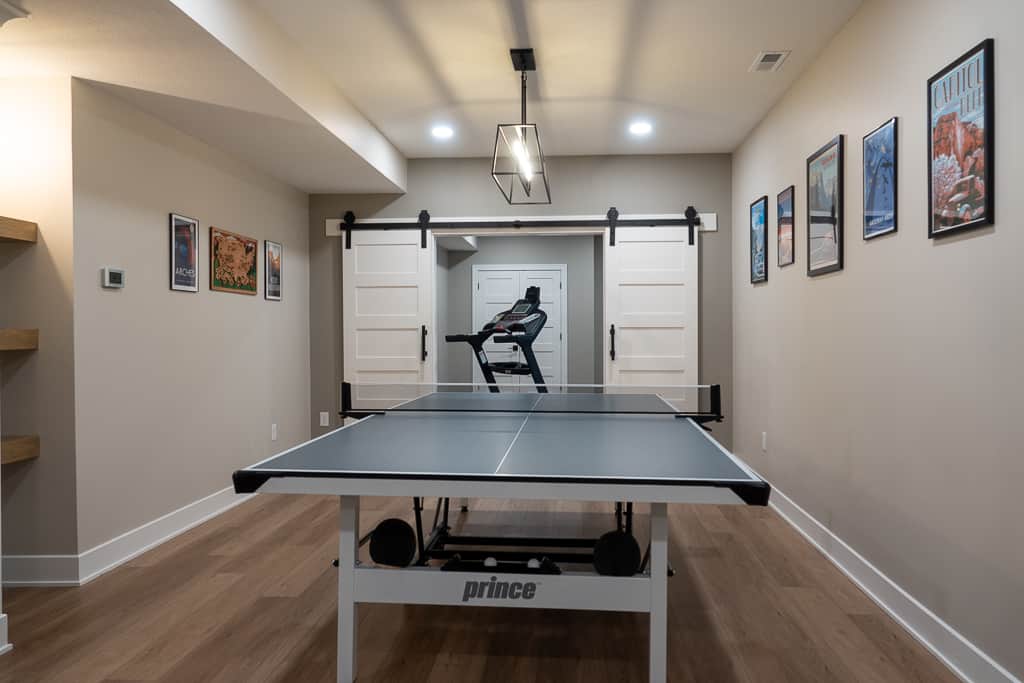 Nicholas Design Build | Ping pong table set up in a home's game room, with a chair on the far end and sports-themed wall decor.