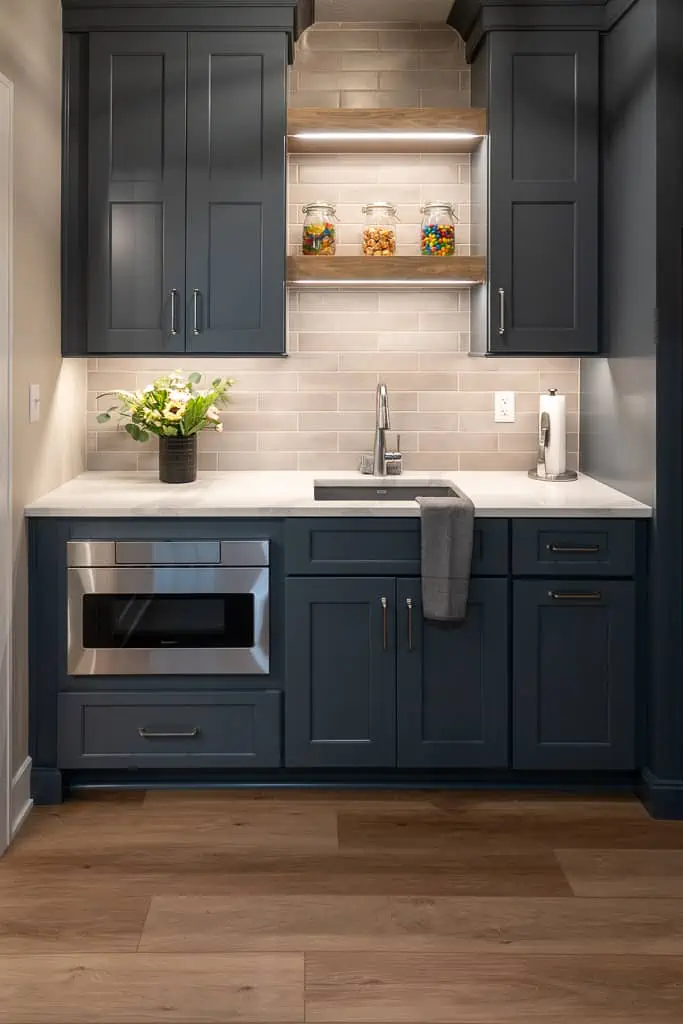 Nicholas Design Build | Modern kitchen corner with navy blue cabinetry, stainless steel appliances, and a bouquet of flowers on the countertop.