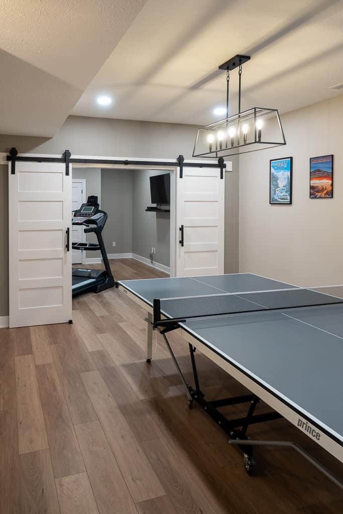 Nicholas Design Build | Modern home recreation room featuring a ping pong table, treadmill, and wall-mounted television.