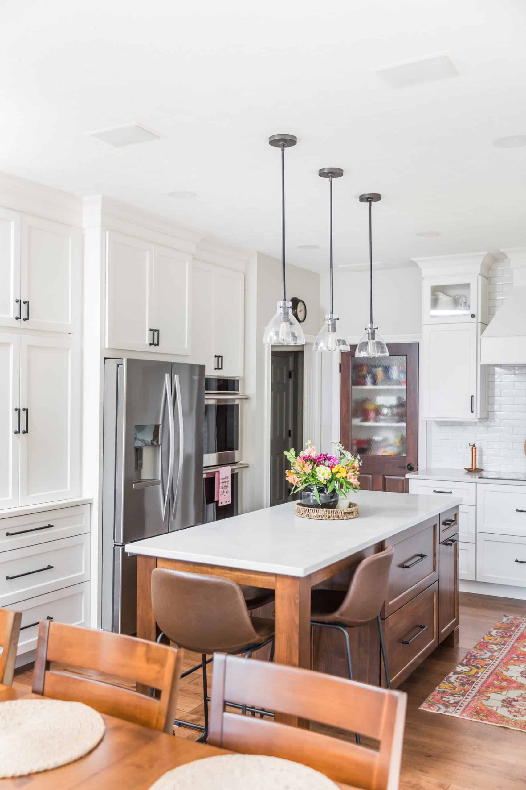 Nicholas Design Build | Modern kitchen with white cabinetry, a central island with seating, stainless steel appliances, and pendant lighting.