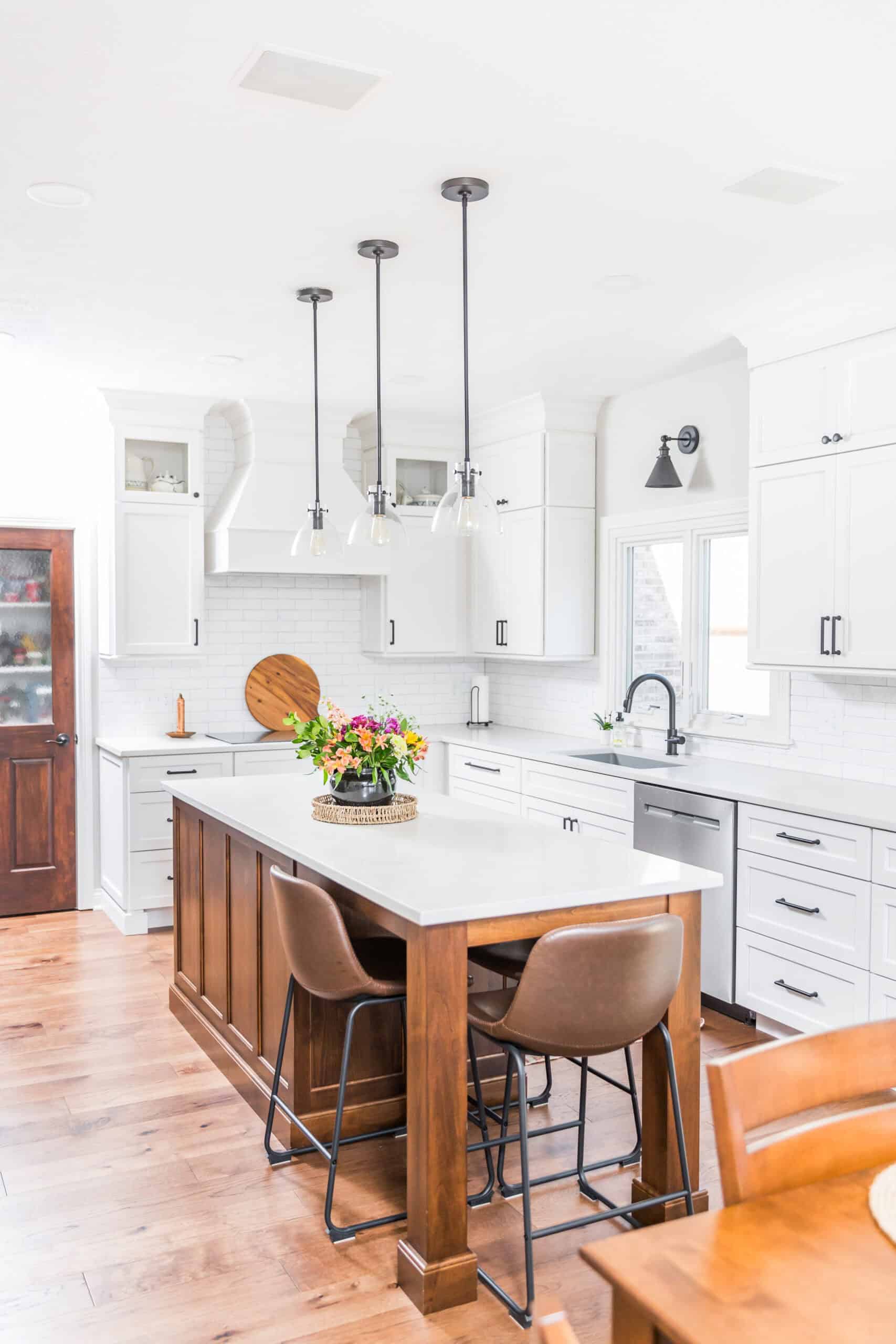 Nicholas Design Build | Bright modern kitchen with white cabinetry, subway tile backsplash, and a wooden island with brown stools.