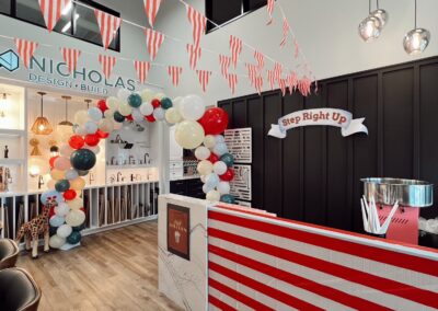 Nicholas Design Build | A brightly decorated indoor space with red and white striped bunting, balloons arranged in an arch, a counter with a 