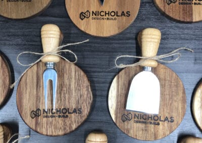 Nicholas Design Build | Several round wood and metal cheese knives and forks, each tied with twine, are arranged on a wooden surface. 