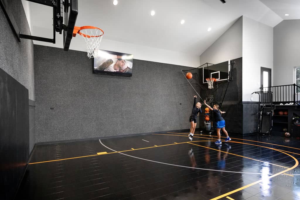 Nicholas Design Build | Two people playing basketball on an indoor court, with one player shooting the ball towards the hoop.